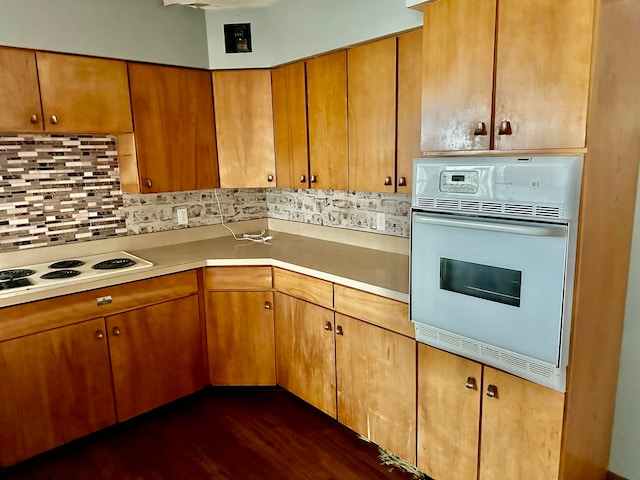 kitchen featuring dark hardwood / wood-style flooring, backsplash, and white appliances