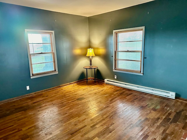 empty room with baseboard heating and hardwood / wood-style floors