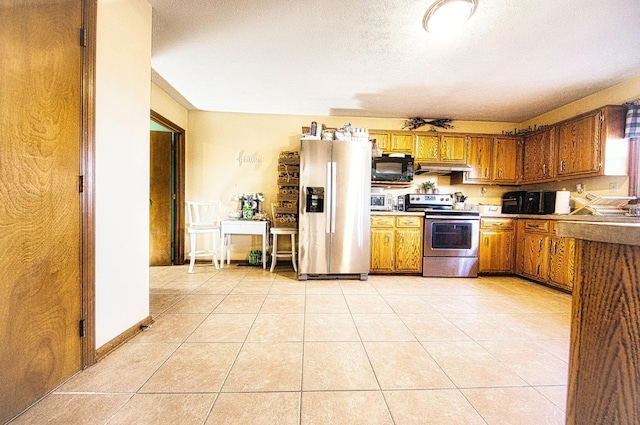 kitchen with light tile patterned flooring, a textured ceiling, stainless steel appliances, and exhaust hood