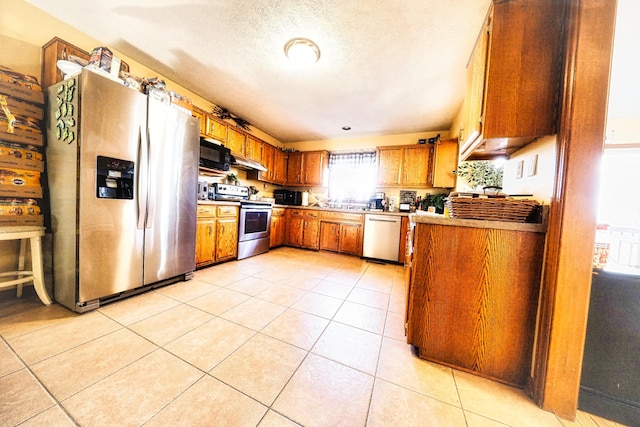 kitchen with appliances with stainless steel finishes, a textured ceiling, and light tile patterned flooring