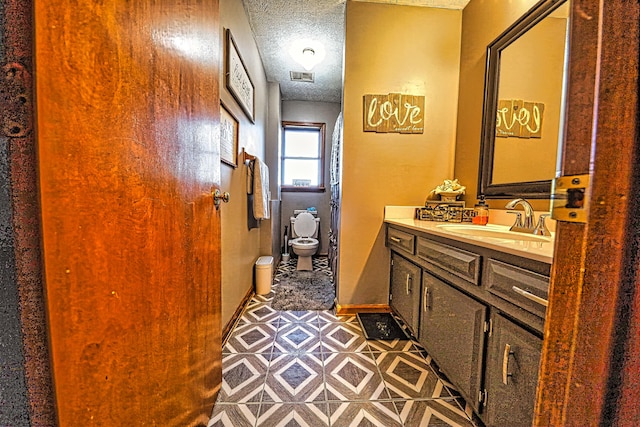 bathroom with vanity, a textured ceiling, toilet, and tile patterned floors