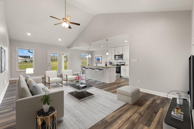 living room with dark hardwood / wood-style flooring, high vaulted ceiling, a wealth of natural light, and ceiling fan