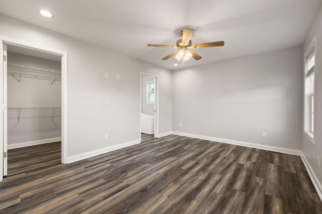 unfurnished bedroom with dark hardwood / wood-style flooring, ceiling fan, a closet, and a spacious closet