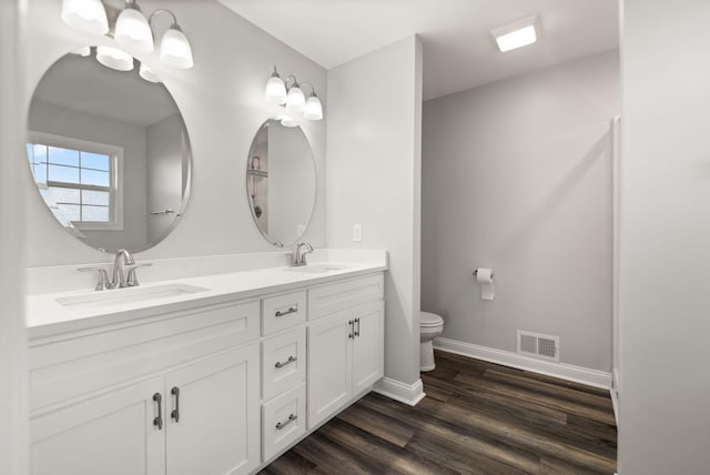 bathroom with a notable chandelier, toilet, wood-type flooring, and vanity