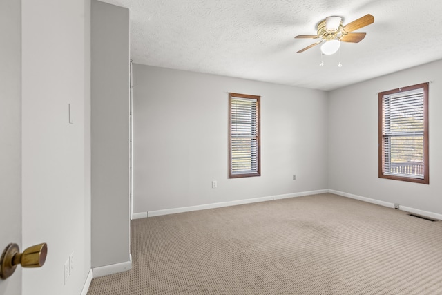 carpeted empty room featuring a textured ceiling, a healthy amount of sunlight, and ceiling fan