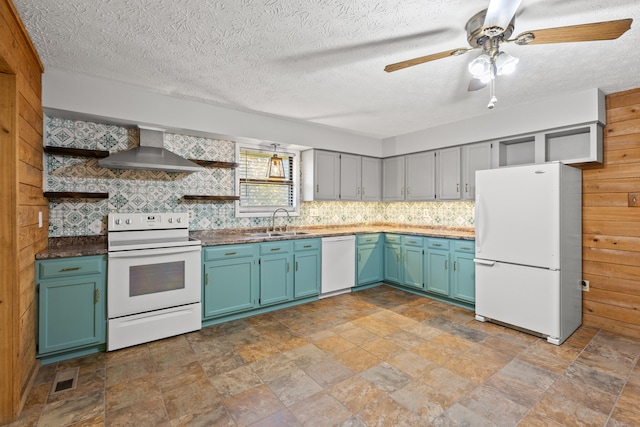 kitchen featuring wall chimney range hood, backsplash, wood walls, sink, and white appliances