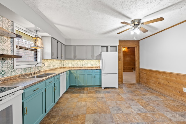 kitchen with white appliances, wood walls, sink, a textured ceiling, and blue cabinetry