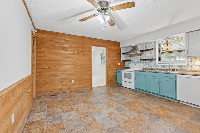 kitchen featuring wooden walls, wall chimney range hood, and white appliances