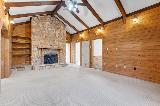 unfurnished living room with carpet floors, lofted ceiling with beams, wooden walls, and a fireplace