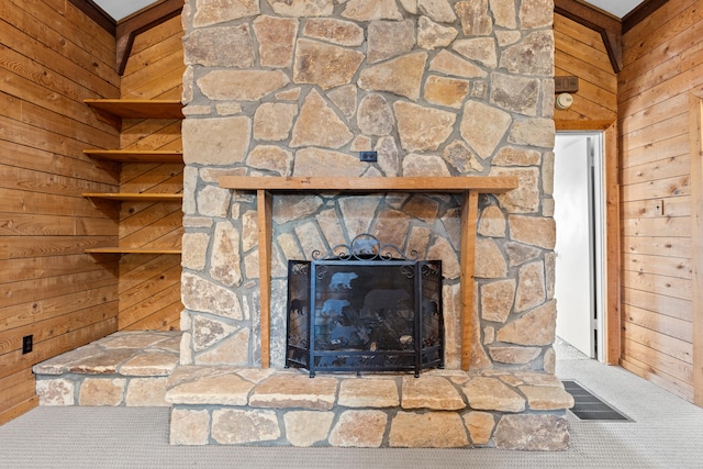 interior details with a stone fireplace, carpet, and wooden walls