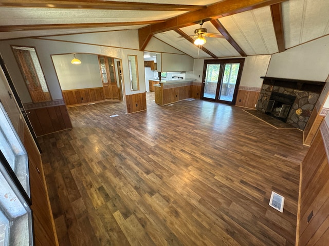 unfurnished living room featuring dark hardwood / wood-style floors, lofted ceiling with beams, ceiling fan, a fireplace, and wood walls