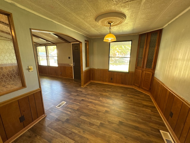 unfurnished dining area featuring a textured ceiling, a wealth of natural light, and dark hardwood / wood-style floors