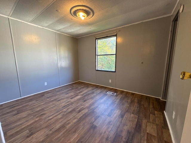 unfurnished room with ornamental molding, dark wood-type flooring, and a textured ceiling