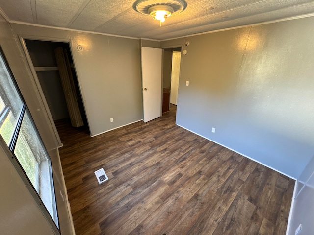 unfurnished bedroom with dark wood-type flooring and a closet