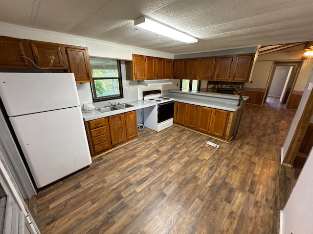 kitchen with a textured ceiling, wood walls, dark wood-type flooring, sink, and white appliances