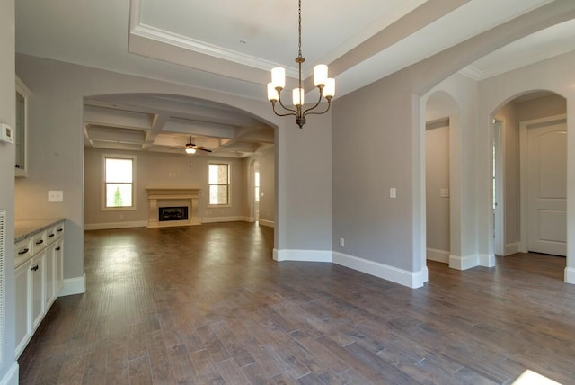 unfurnished living room with coffered ceiling, dark hardwood / wood-style floors, beamed ceiling, ornamental molding, and ceiling fan with notable chandelier