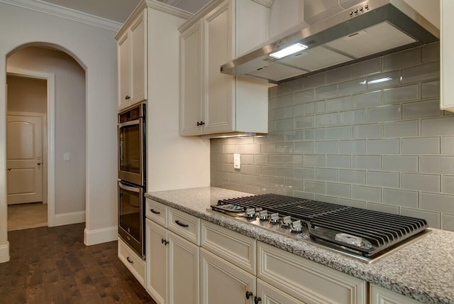 kitchen featuring decorative backsplash, wall chimney range hood, stainless steel appliances, ornamental molding, and dark hardwood / wood-style flooring