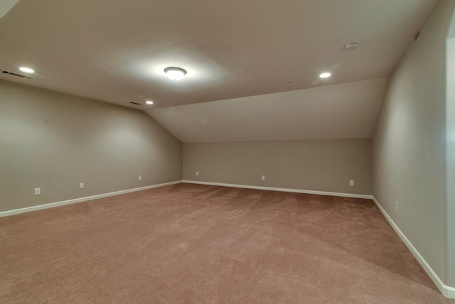 additional living space featuring vaulted ceiling and light colored carpet