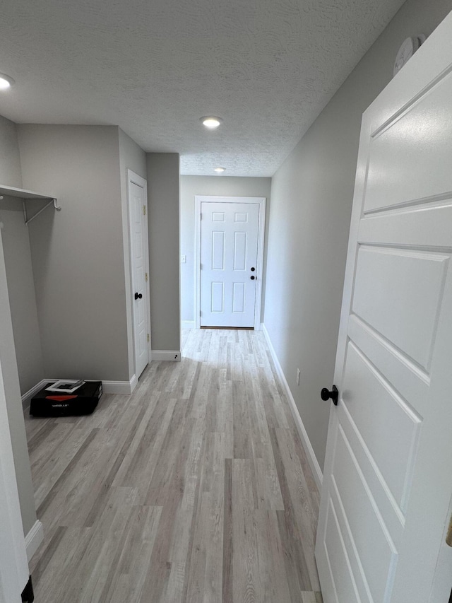 corridor with light hardwood / wood-style flooring and a textured ceiling