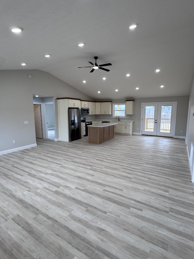 kitchen with appliances with stainless steel finishes, a kitchen island, light hardwood / wood-style flooring, and lofted ceiling