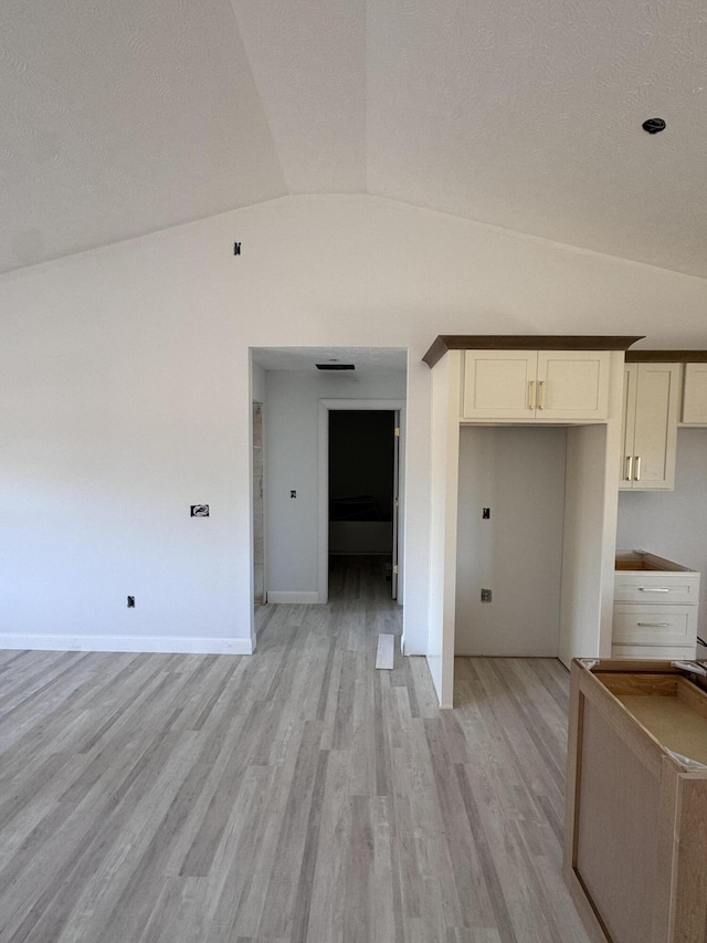 empty room with vaulted ceiling and light wood-type flooring