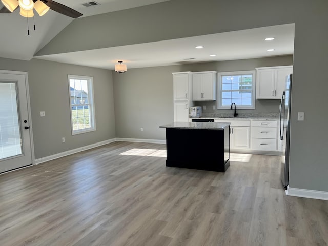 kitchen with white cabinetry, a center island, light wood-type flooring, and baseboards