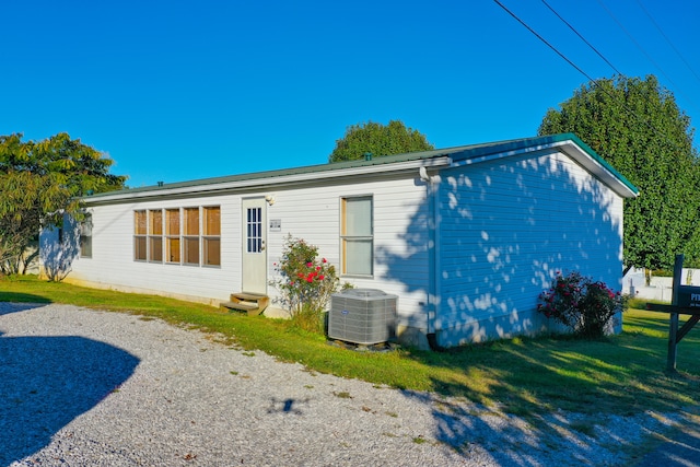 rear view of house featuring central AC and a lawn