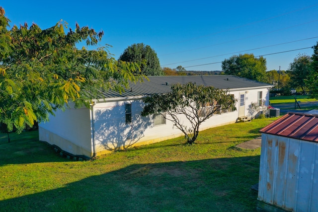 view of side of home featuring a yard, a storage shed, and central air condition unit