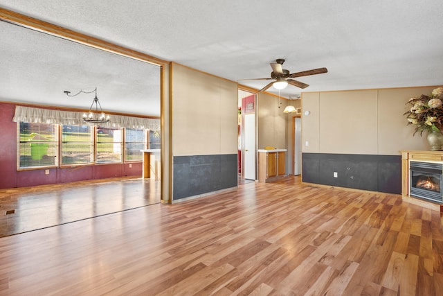 unfurnished living room featuring a textured ceiling, light hardwood / wood-style flooring, and ceiling fan with notable chandelier