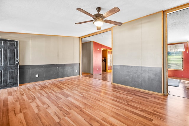 empty room featuring ceiling fan, a textured ceiling, and light hardwood / wood-style flooring