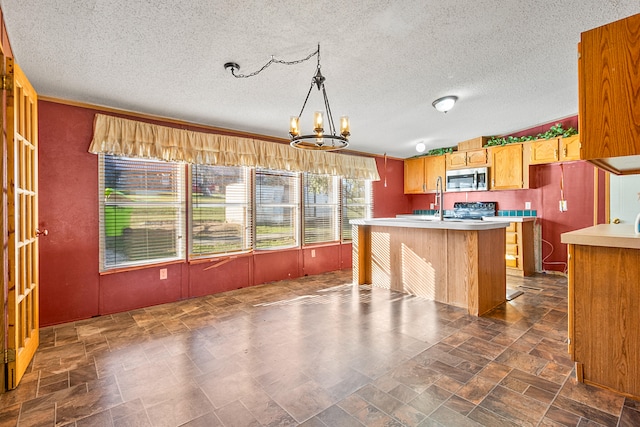 kitchen featuring a textured ceiling, a chandelier, a center island, and pendant lighting