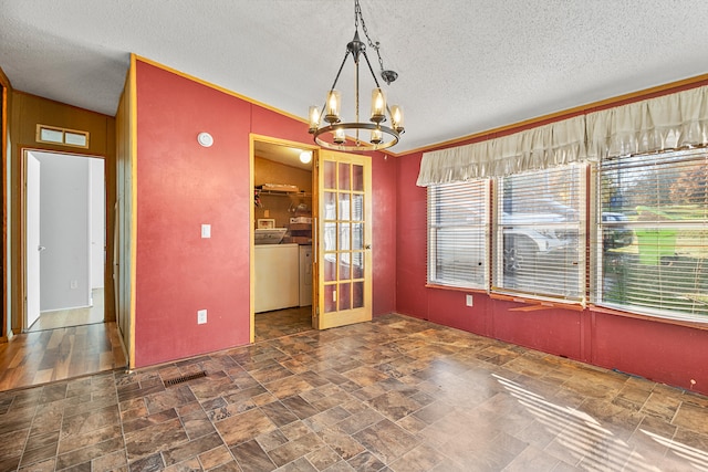 unfurnished dining area with lofted ceiling, washer / clothes dryer, crown molding, an inviting chandelier, and a textured ceiling