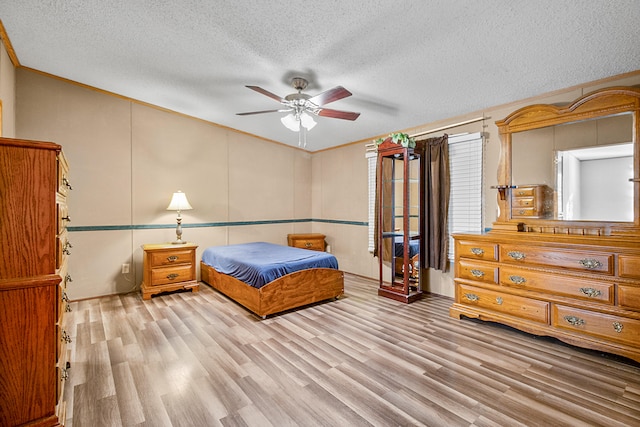 bedroom featuring ornamental molding, a textured ceiling, light wood-type flooring, and ceiling fan