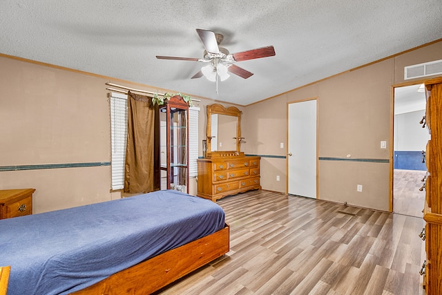 bedroom with ceiling fan, a textured ceiling, ornamental molding, and light wood-type flooring