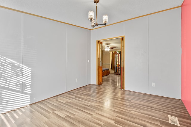 unfurnished room with ceiling fan with notable chandelier, a textured ceiling, lofted ceiling, crown molding, and light hardwood / wood-style flooring