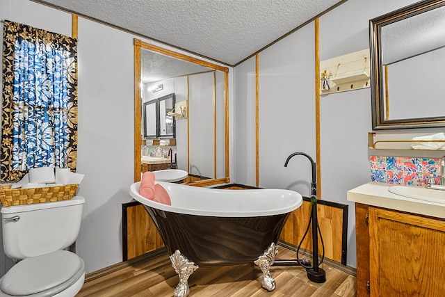 bathroom featuring toilet, hardwood / wood-style floors, vanity, a textured ceiling, and a bath