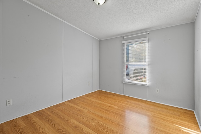 spare room with ornamental molding, a textured ceiling, and wood-type flooring