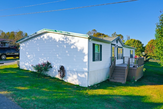 view of side of home with a deck and a lawn