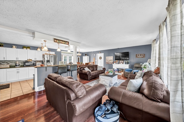 living room with a textured ceiling, an inviting chandelier, and dark hardwood / wood-style flooring