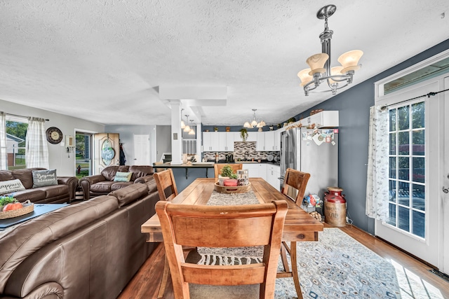 dining room featuring a textured ceiling, an inviting chandelier, and light wood-type flooring