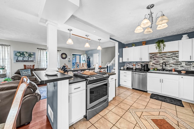 kitchen with decorative backsplash, stainless steel appliances, decorative light fixtures, white cabinets, and a textured ceiling