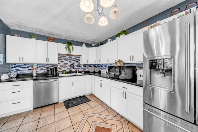 kitchen featuring backsplash, a textured ceiling, hanging light fixtures, stainless steel appliances, and white cabinets