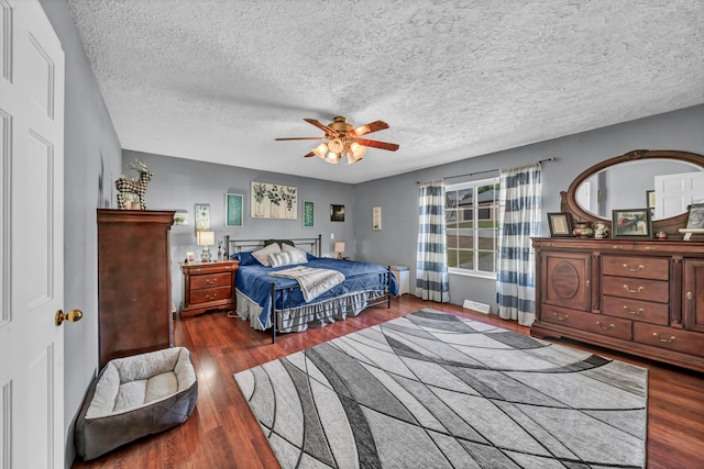 bedroom featuring a textured ceiling, dark wood-type flooring, and ceiling fan