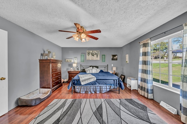 bedroom with ceiling fan, a textured ceiling, and hardwood / wood-style floors