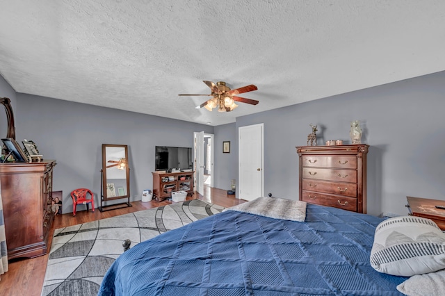 bedroom featuring light hardwood / wood-style floors, a textured ceiling, and ceiling fan