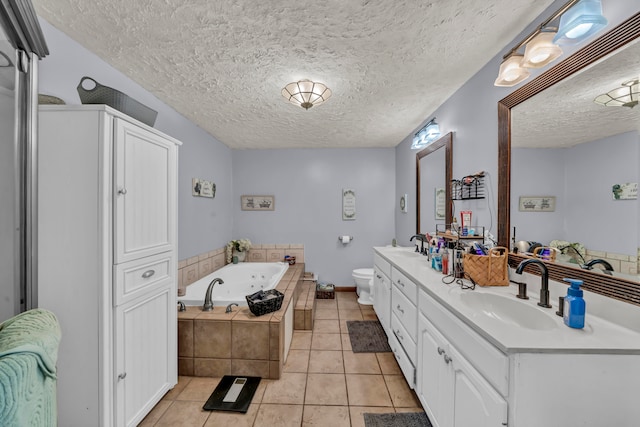 bathroom featuring a relaxing tiled tub, a textured ceiling, toilet, vanity, and tile patterned flooring