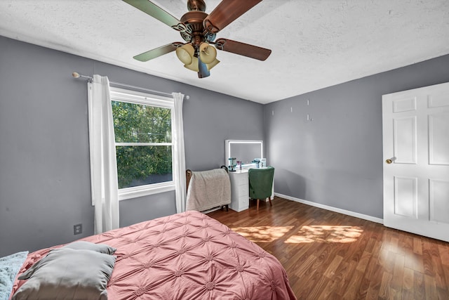 bedroom with a textured ceiling, dark wood-type flooring, and ceiling fan