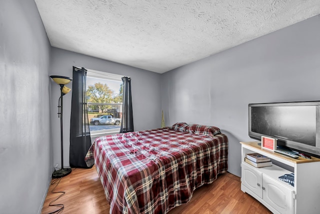 bedroom featuring a textured ceiling and light hardwood / wood-style flooring