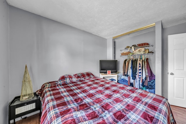 bedroom featuring hardwood / wood-style floors, a textured ceiling, and a closet