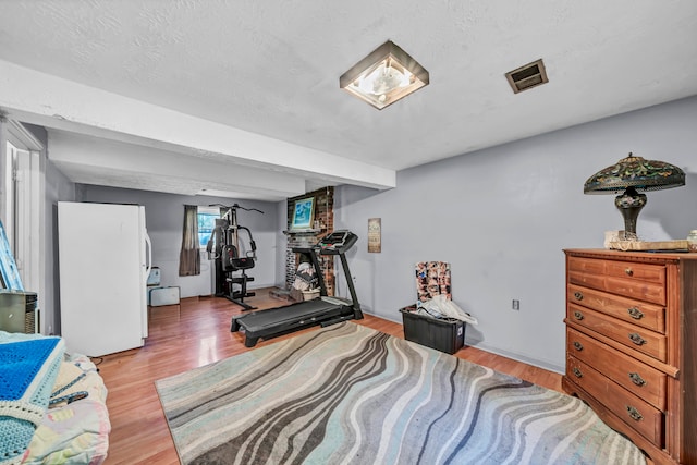 workout room with light hardwood / wood-style floors and a textured ceiling